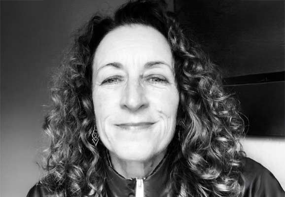 A black and white image of a person with curly hair smiling.